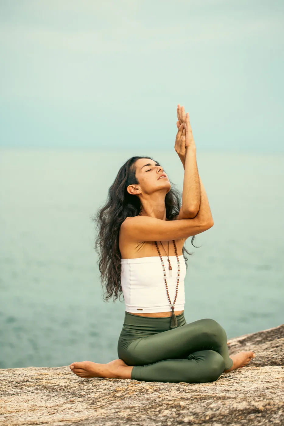 Marcela seated by the sea, hands in prayer
